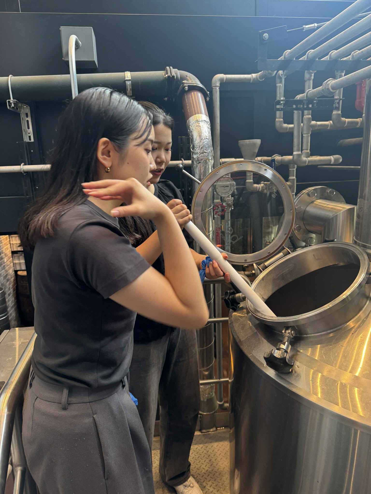 クラフトビール「THE FISH」の仕込み工程でタンク内をかき混ぜる作業体験する横浜市立大生